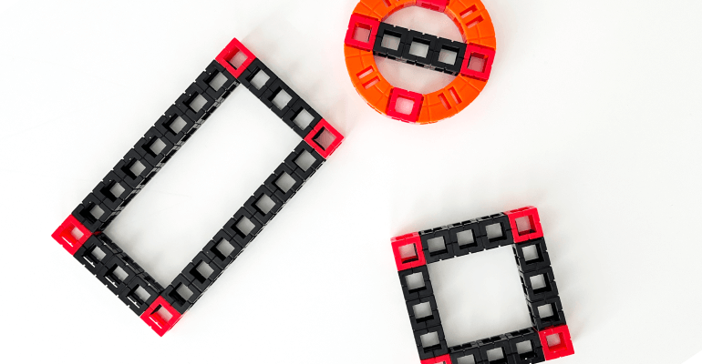 Black and red learning blocks laid out on a table. Some blocks form a rectangle