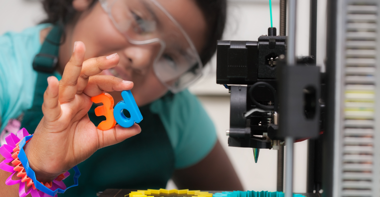 Young girl with 3D printed letters "d" and "e" held in front of her in her hands