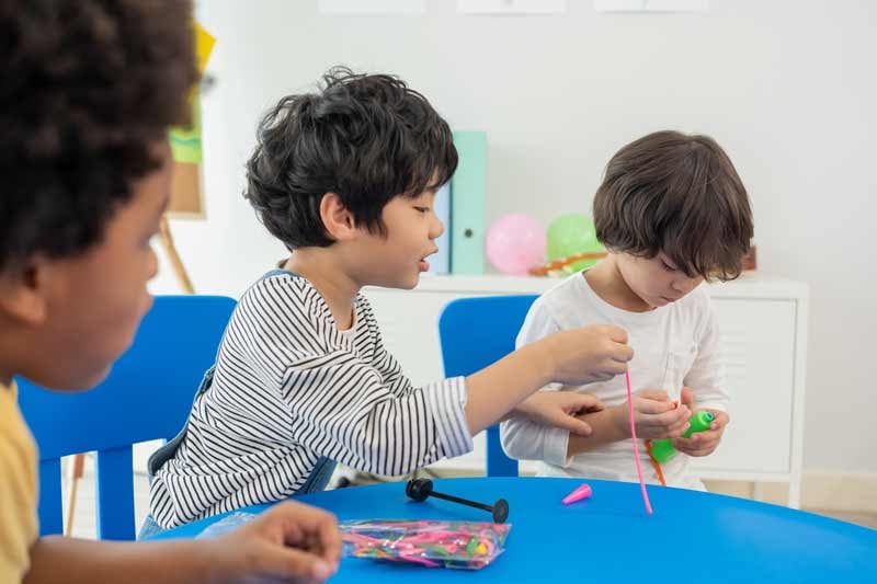 Kindergarten students working together with various tools to solve STEM problems